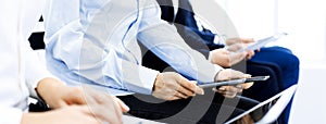 Group of business people sitting in office waiting for job interview, close-up. Hands of woman working on laptop