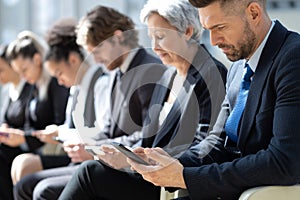 Group of business people with smartphones sitting in a row