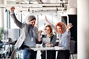 A group of business people standing in an office, expressing excitement.