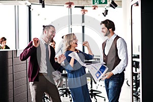 A group of business people standing in an office, expressing excitement.