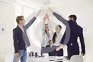 Group of business people standing smiling raised their hands up happy standing at a table in the office.