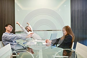 Group of business people stretching in meeting room with blank p