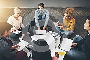 Group of business people talking, planning with documents and sitting in a meeting on floor in an office together at