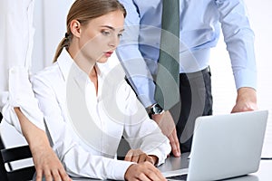 Group of business people using laptop computer while standing in office. Meeting and teamwork concept