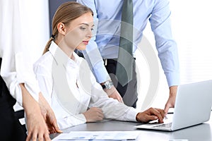 Group of business people using laptop computer while standing in office. Meeting and teamwork concept