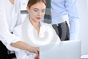 Group of business people using laptop computer while standing in office. Meeting and teamwork concept