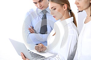 Group of business people using laptop computer while standing in office. Meeting and teamwork concept