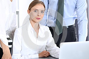 Group of business people using laptop computer while standing in office. Meeting and teamwork concept