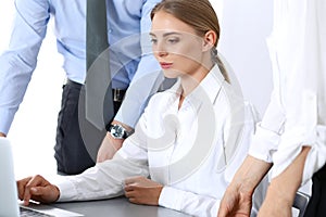 Group of business people using laptop computer while standing in office. Meeting and teamwork concept