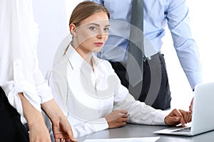 Group of business people using laptop computer while standing in office. Meeting and teamwork concept