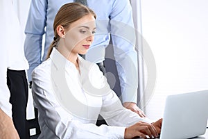 Group of business people using laptop computer while standing in office. Meeting and teamwork concept