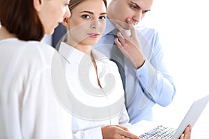 Group of business people using laptop computer while standing in office. Meeting and teamwork concept