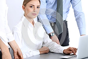 Group of business people using laptop computer while standing in office. Meeting and teamwork concept