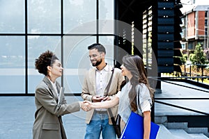 Group of business people walk outside in front of office buildings. Businessman and two businesswomen sharing experience ideas and
