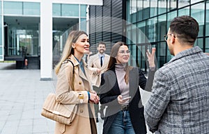 Group of business people walking outside in front of office building. Colleagues discussing on the way to the work. Young