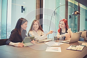 Group of business women meeting in a meeting room with blank screen, sharing their ideas, Multi ethnic