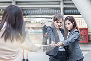 Group of business women pulling a rope competing with commitment to winer