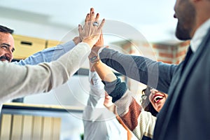 Group of business workers standing with hands together highing five at the office