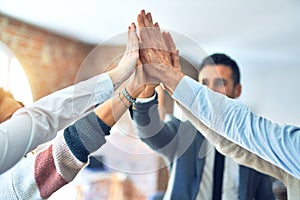 Group of business workers standing with hands together highing five at the office