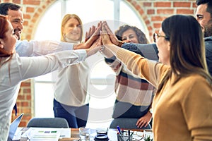Group of business workers standing with hands together highing five at the office