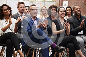 Group Of Businessmen And Businesswomen Applauding Presentation At Conference