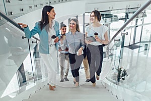 Businessmen and businesswomen walking and taking stairs in an office building