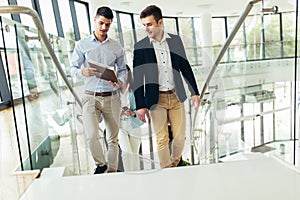 Businessmen and businesswomen walking and taking stairs in an office building