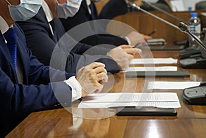 A group of businessmen or officials at a business meeting during a pandemic. Men in suits and medical masks. Reportage