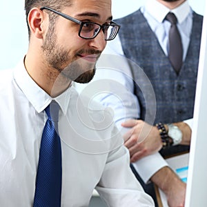 Group of businessmen point arm with silver pen at laptop pc