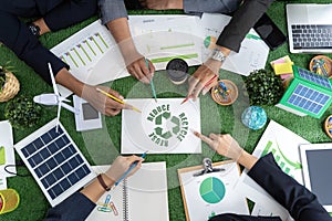 Group of businessmen's hands touching green recycling symbol, showing a mockup of green earth with recycling icons