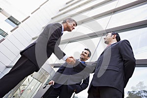 Group of businessmen shaking hands outside office