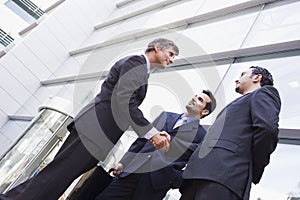 Group of businessmen shaking hands outside office