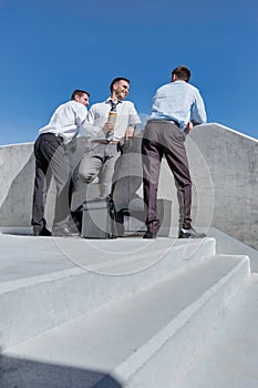 Group of businessmen standing and talking while drinking coffee during break