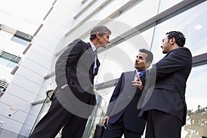 Group of businessmen talking outside office buildi