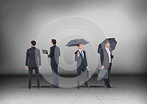 Group of Businessmen with umbrellas looking in opposite directions