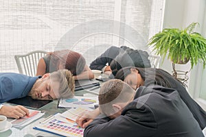 Group businessmen and women sleeping resting on workplace during work meeting, concept of exhausted businesspeople bored