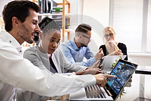 Group Of Businesspeople Examining Graph On Computer