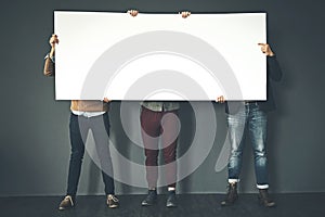 Group of businesspeople holding up a copyspace sign voicing their opinion at work with a grey background. People with photo