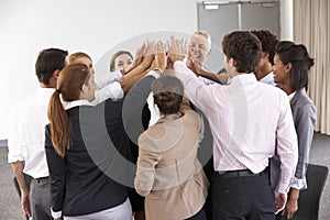 Group Of Businesspeople Joining Hands In Circle At Company Seminar