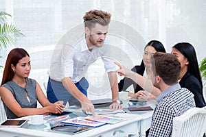 Group of businesspeople looking at businessman blaming his colleague in meeting