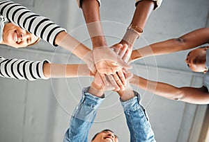Group of businesspeople piling their hands together in an office at work. Business professionals having fun standing