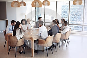 Group Of Businesspeople Sitting Around Table In Meeting Room