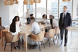 Group Of Businesspeople Sitting Around Table In Meeting Room