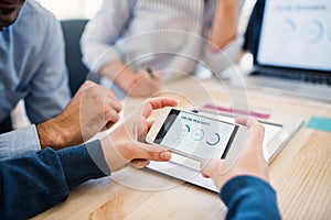 Group of businesspeople with smartphone working together in office, midsection.