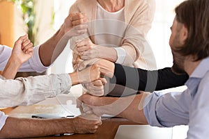 Group of businesspeople stack fists together enjoy funny teambuilding activity