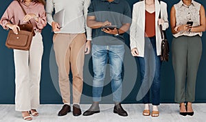 Group of businesspeople standing in a row in an office together. Five business professionals standing using technology