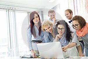 Group of businesspeople using laptop at desk in creative office