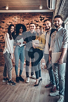 Group of businesspeople using wireless technology together while standing near brick wall