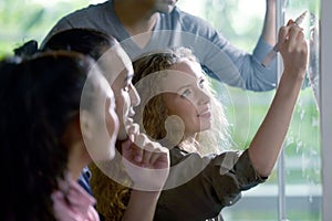 Group of businesspersons discussing work and using glass board