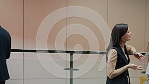 Group of businesswomen and businessmen talking standing in office lobby